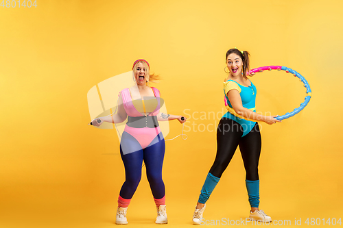 Image of Young caucasian plus size female models training on yellow background