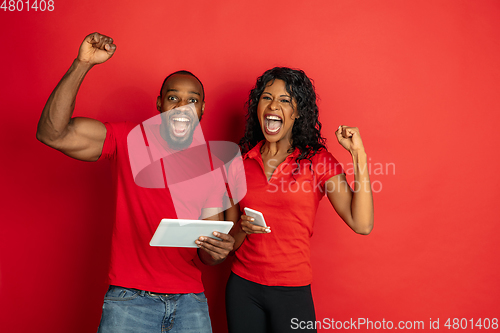 Image of Young emotional african-american man and woman on red background