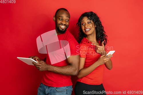 Image of Young emotional african-american man and woman on red background