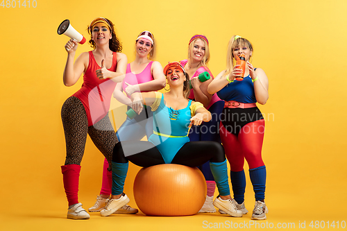 Image of Young caucasian plus size female models training on yellow background
