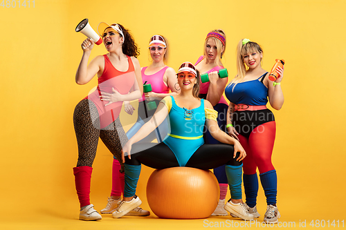 Image of Young caucasian plus size female models training on yellow background