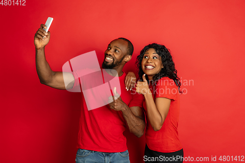 Image of Young emotional african-american man and woman on red background