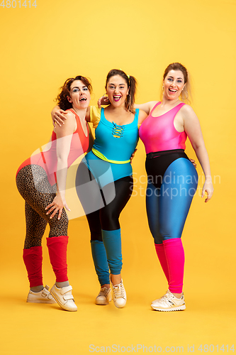Image of Young caucasian plus size female models training on yellow background
