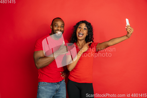 Image of Young emotional african-american man and woman on red background