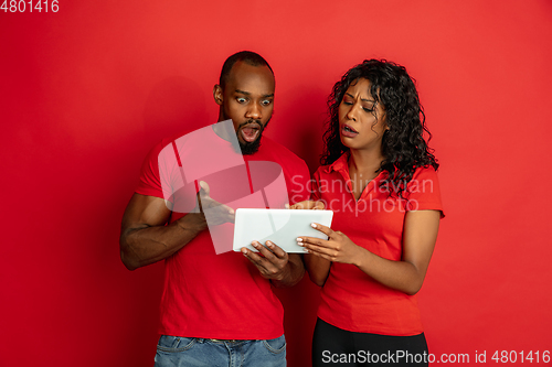 Image of Young emotional african-american man and woman on red background