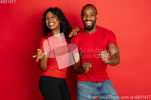 Image of Young emotional african-american man and woman on red background