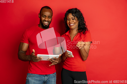 Image of Young emotional african-american man and woman on red background