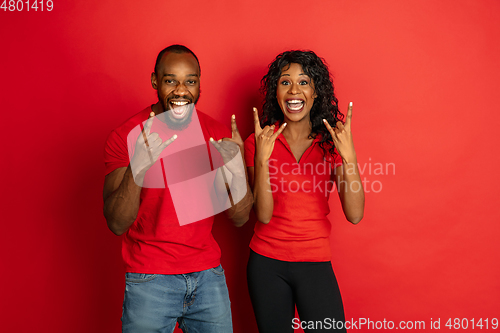 Image of Young emotional african-american man and woman on red background
