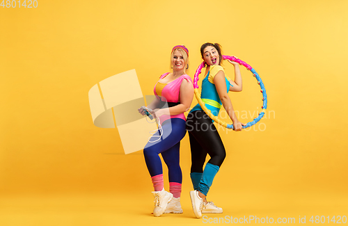 Image of Young caucasian plus size female models training on yellow background