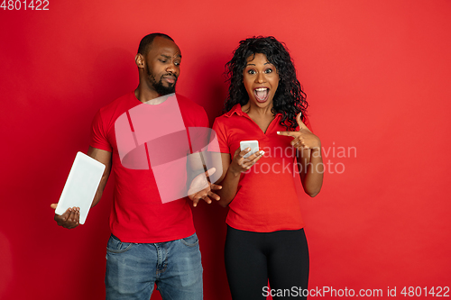 Image of Young emotional african-american man and woman on red background