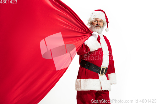 Image of Santa Claus pulling huge bag full of christmas presents isolated on white background