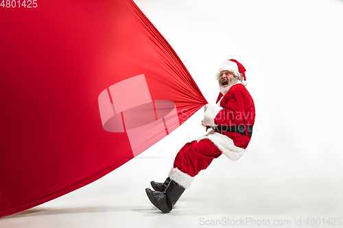 Image of Santa Claus pulling huge bag full of christmas presents isolated on white background