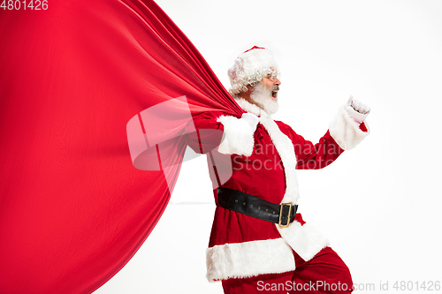 Image of Santa Claus pulling huge bag full of christmas presents isolated on white background