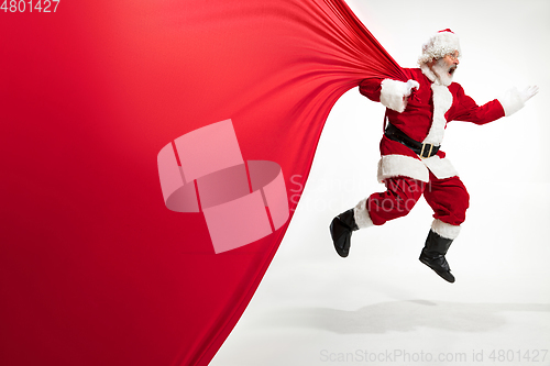 Image of Santa Claus pulling huge bag full of christmas presents isolated on white background