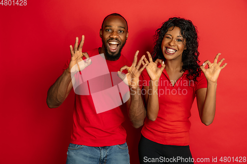 Image of Young emotional african-american man and woman on red background