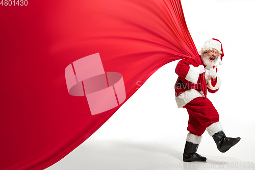 Image of Santa Claus pulling huge bag full of christmas presents isolated on white background