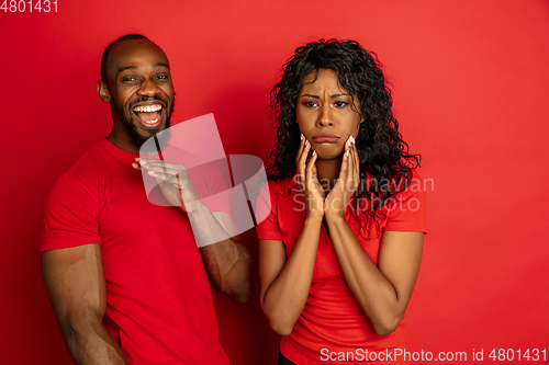 Image of Young emotional african-american man and woman on red background