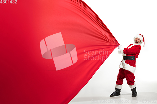 Image of Santa Claus pulling huge bag full of christmas presents isolated on white background