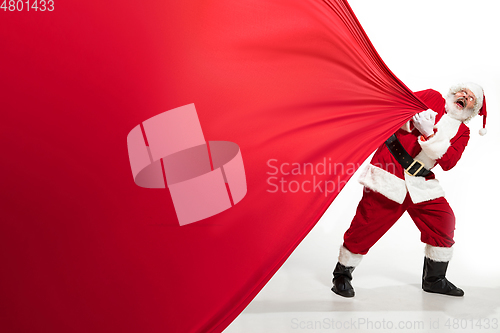 Image of Santa Claus pulling huge bag full of christmas presents isolated on white background