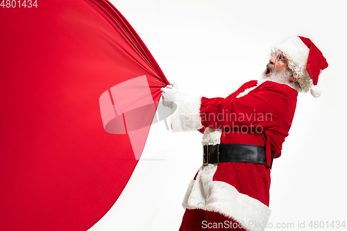 Image of Santa Claus pulling huge bag full of christmas presents isolated on white background