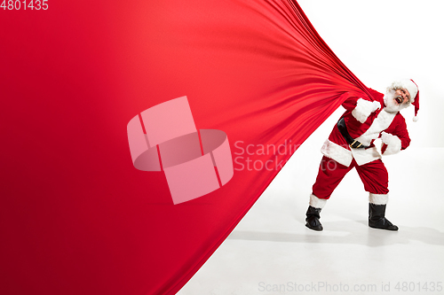 Image of Santa Claus pulling huge bag full of christmas presents isolated on white background