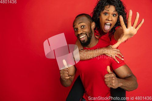 Image of Young emotional african-american man and woman on red background