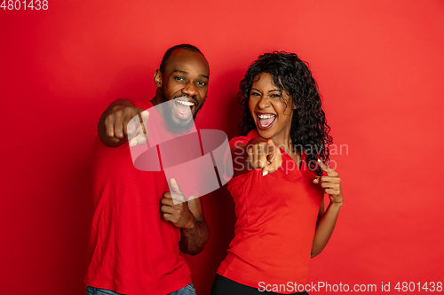 Image of Young emotional african-american man and woman on red background