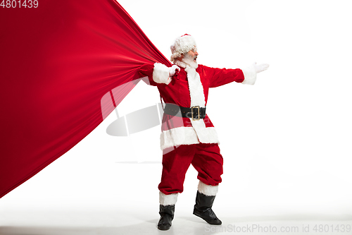 Image of Santa Claus pulling huge bag full of christmas presents isolated on white background