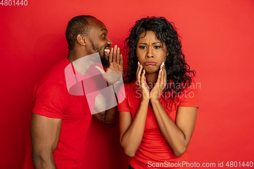 Image of Young emotional african-american man and woman on red background