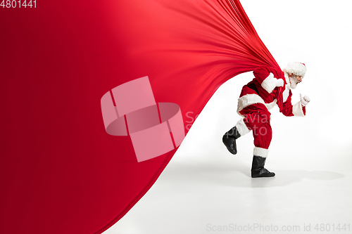 Image of Santa Claus pulling huge bag full of christmas presents isolated on white background