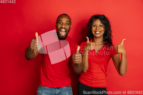 Image of Young emotional african-american man and woman on red background