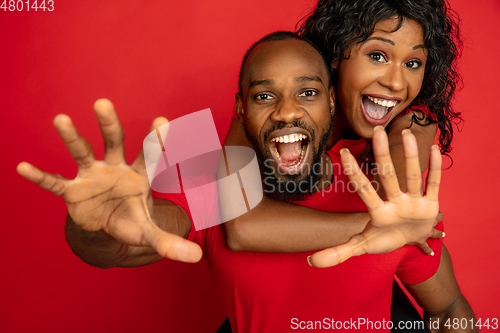 Image of Young emotional african-american man and woman on red background