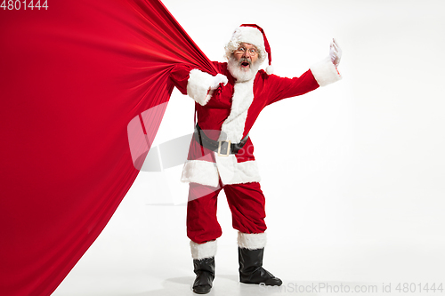 Image of Santa Claus pulling huge bag full of christmas presents isolated on white background