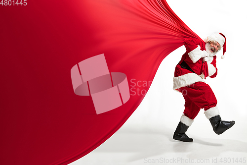 Image of Santa Claus pulling huge bag full of christmas presents isolated on white background