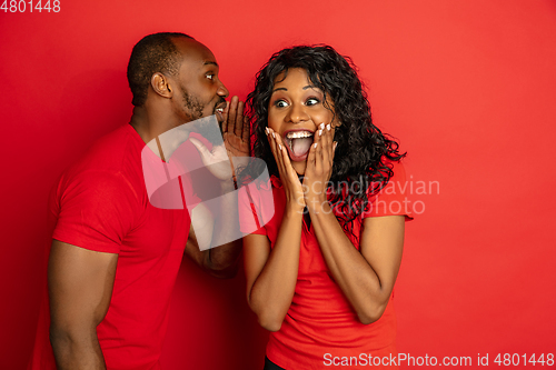 Image of Young emotional african-american man and woman on red background