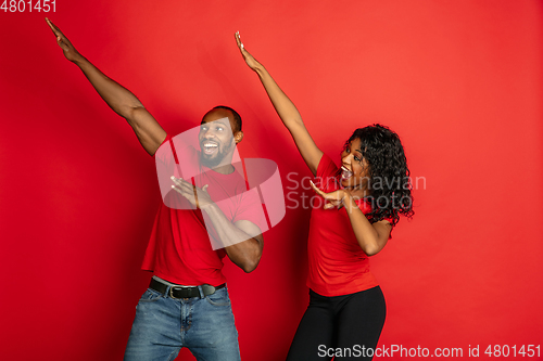 Image of Young emotional african-american man and woman on red background