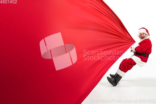 Image of Santa Claus pulling huge bag full of christmas presents isolated on white background