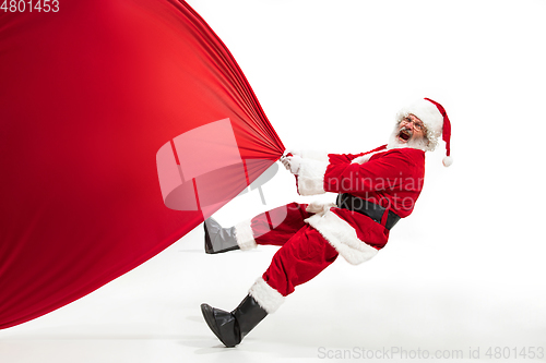 Image of Santa Claus pulling huge bag full of christmas presents isolated on white background