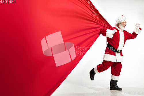 Image of Santa Claus pulling huge bag full of christmas presents isolated on white background