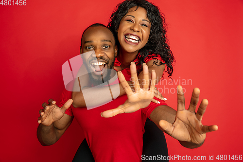 Image of Young emotional african-american man and woman on red background