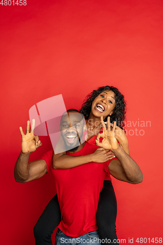 Image of Young emotional african-american man and woman on red background