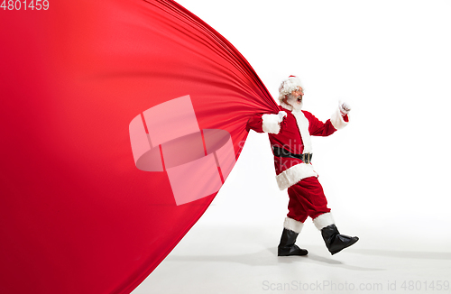Image of Santa Claus pulling huge bag full of christmas presents isolated on white background