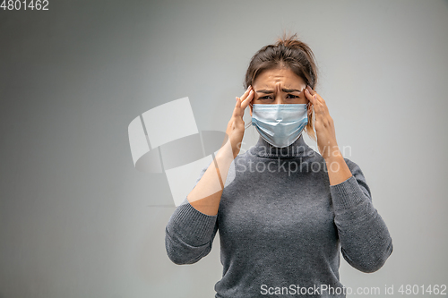 Image of Caucasian woman wearing the respiratory protection mask against air pollution and dusk on grey studio background