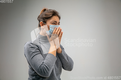 Image of Caucasian woman wearing the respiratory protection mask against air pollution and dusk on grey studio background