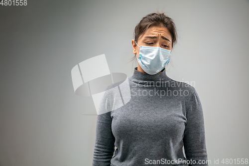 Image of Caucasian woman wearing the respiratory protection mask against air pollution and dusk on grey studio background