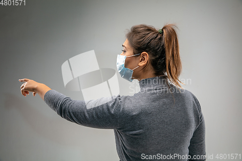 Image of Caucasian woman wearing the respiratory protection mask against air pollution and dusk on grey studio background