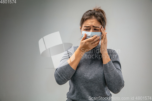 Image of Caucasian woman wearing the respiratory protection mask against air pollution and dusk on grey studio background