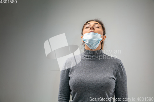 Image of Caucasian woman wearing the respiratory protection mask against air pollution and dusk on grey studio background