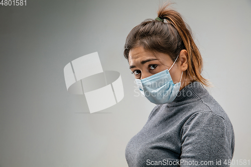 Image of Caucasian woman wearing the respiratory protection mask against air pollution and dusk on grey studio background