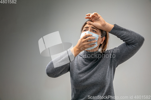 Image of Caucasian woman wearing the respiratory protection mask against air pollution and dusk on grey studio background